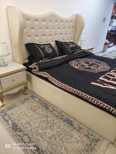 um quarto com uma cama com uma cabeceira branca e uma mesa em El massa Quit apartment em Sharjah