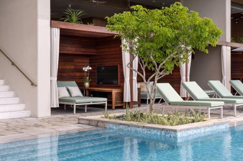 a pool with lounge chairs and a tv next to a house at The Ritz-Carlton Residences, Waikiki Beach Hotel in Honolulu