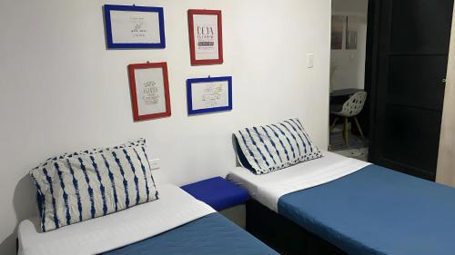 Habitación con 2 camas, silla y cuadros en la pared. en BORA, Apto 301 Tu Espacio Fuera de Casa, en Ibagué
