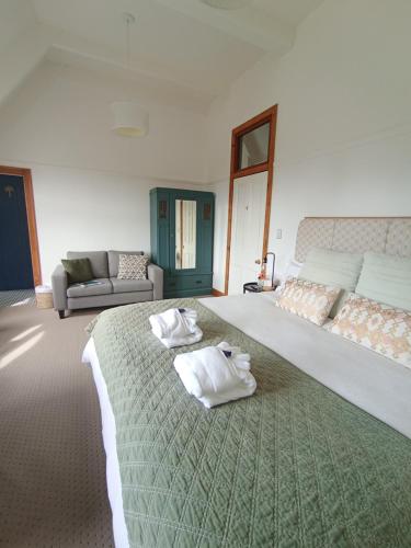 a bedroom with a large bed with towels on it at Kingsdown Manor B&B Timaru in Timaru