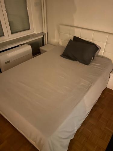 un grande letto bianco con un cuscino nero sopra di Flat @Mechelen centrum a Mechelen