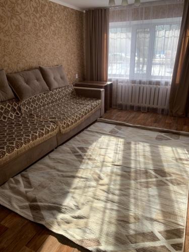 a living room with a bed and a window at трёхкомнатная после ремонта с удобным расположением in Karagandy