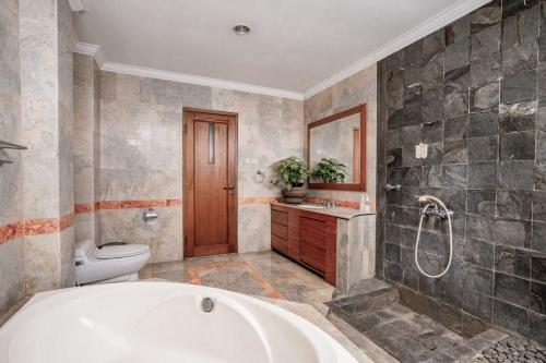 a bathroom with a bath tub and a toilet at Pasteur Beautiful Luxury Home in Bandung