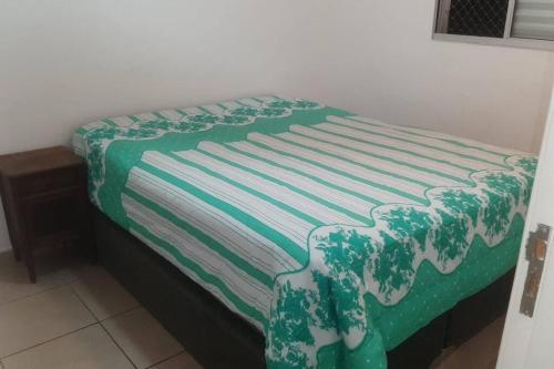 Una cama con una manta verde y blanca. en Apartamento 2Q, 5 pessoas excelente localização en Bauru