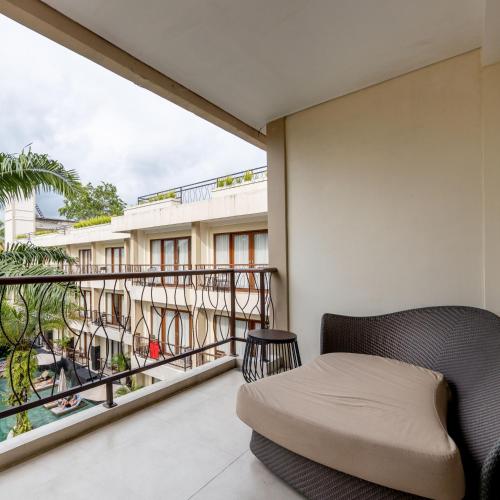 a balcony with a bed and a view of a building at Anumana Ubud Hotel in Ubud