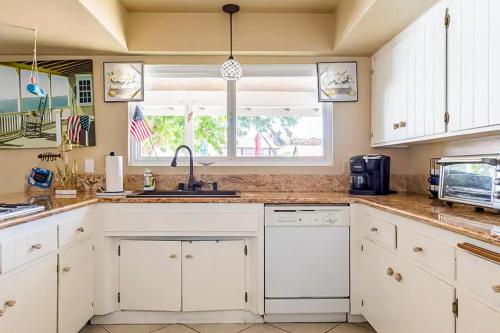 a kitchen with white cabinets and a sink and a window at Lake Life Home in Victorville