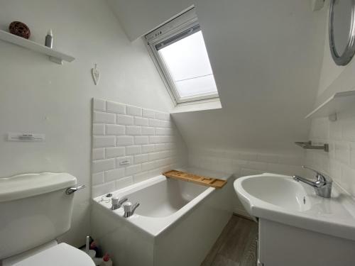 a white bathroom with a tub and a sink at Beautiful cottage in tranquil location with large garden in Woolacombe