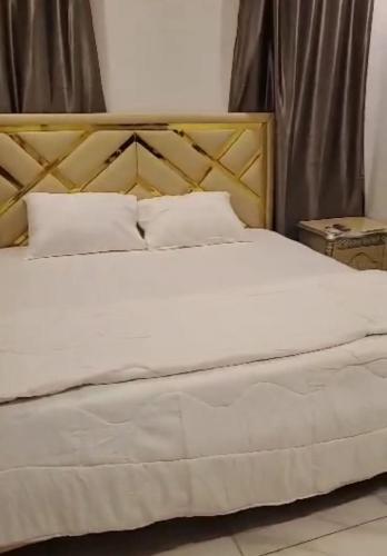a bedroom with a white bed with a wooden headboard at Luxurious Home - Isheri Magodo in Agege