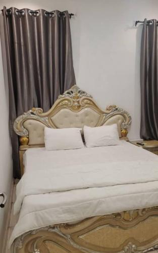 una camera da letto con letto oro e bianco con tende di Luxurious Home - Isheri Magodo ad Agege