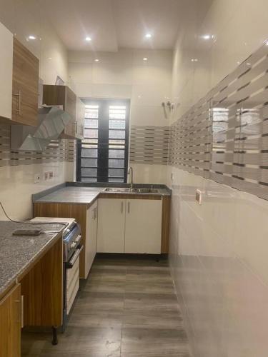 a large kitchen with white cabinets and a sink at Luxurious Home - Isheri Magodo in Agege
