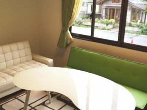 a room with a white table and a couch and a window at Casa Allegra in Yamanakako