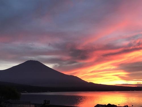 a sunset over a lake with a mountain in the background at Casa Allegra in Yamanakako