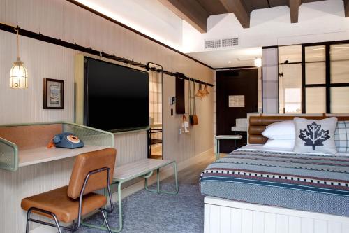 a bedroom with a bed and a desk and a television at Moxy Banff in Banff