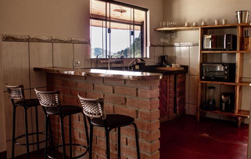 un bar con sgabelli in una stanza con muro di mattoni di Chalé Vista do Paraíso a Gonçalves