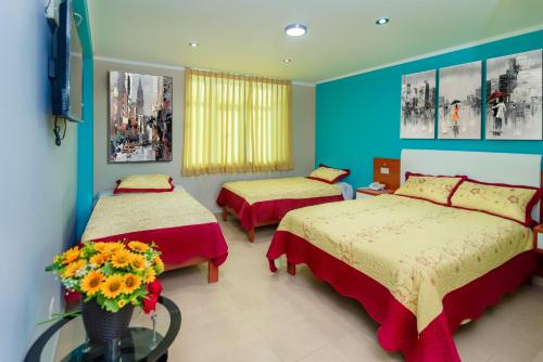 a bedroom with two beds and a vase of flowers at HOSTAL TAU TACNA in Tacna