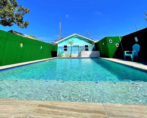 basen przed zielonym płotem w obiekcie The Poolside Bungalow w mieście Galveston
