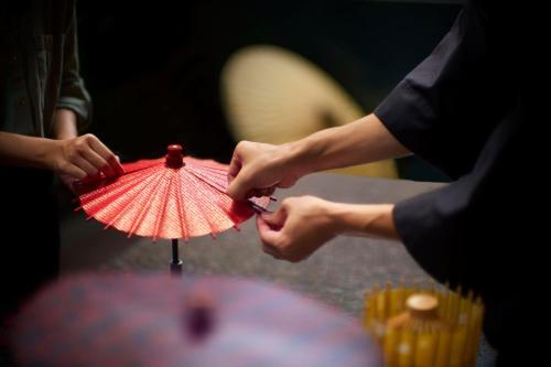 a person is holding a red paper umbrella at The Ritz-Carlton Kyoto in Kyoto