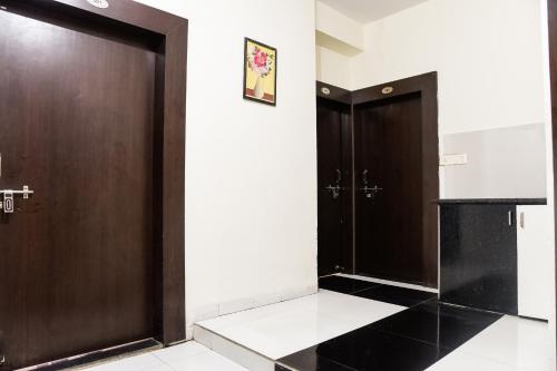 Cette chambre dispose de 2 portes en bois et de murs blancs. dans l'établissement OYO Radhika Palace, à Bhopal