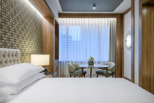 um quarto com uma cama branca, uma mesa e uma janela em AC Hotel Cuzco by Marriott em Madrid