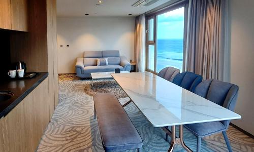 een woonkamer met een eettafel en een bank bij Saint Beach Hotel in Jeju-stad