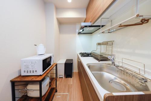 uma cozinha com um lavatório e um micro-ondas em La Terrasse Higashikomagata - Vacation STAY 17380v em Tóquio