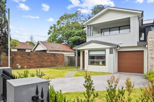 a white house with a brown garage at Luxury Retreat & Spacious 4BR House in Willoughby in Sydney