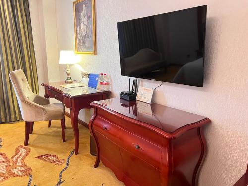 a hotel room with a desk with a television on a wall at Foshan Shiwan Hotel in Foshan