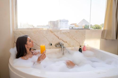 a woman sitting in a bath tub with a glass of orange juice at king of pharaohs pyramids view in Cairo