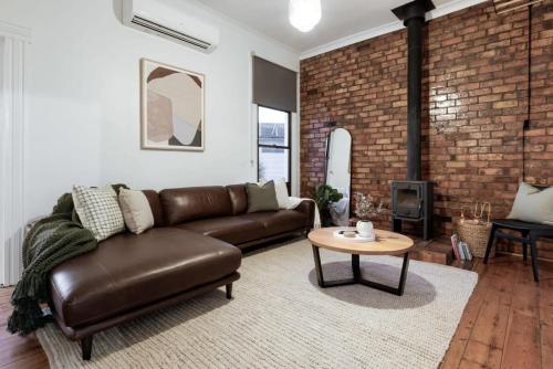 a living room with a leather couch and a table at Charming Cottage Near The City With Parking in Launceston