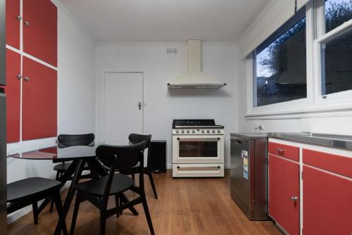a kitchen with red cabinets and a table and chairs at Charming Cottage Near The City With Parking in Launceston