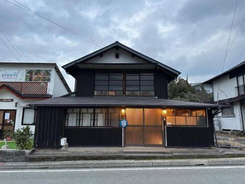 a black house with a lot of windows at Momiji hostel in Minami Aso
