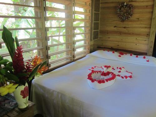a room with a bed with red flowers on it at Hotel Chillies and Native Sons Diving in West End