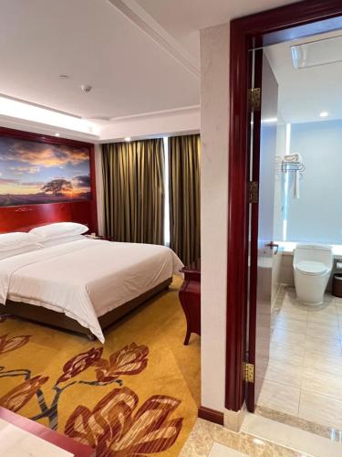 a bedroom with a bed with a painting on the wall at Foshan Shiwan Hotel in Foshan