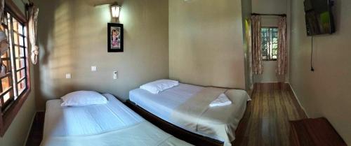 two twin beds in a room with at Blue Moon Guesthouse and Bar in Kampot