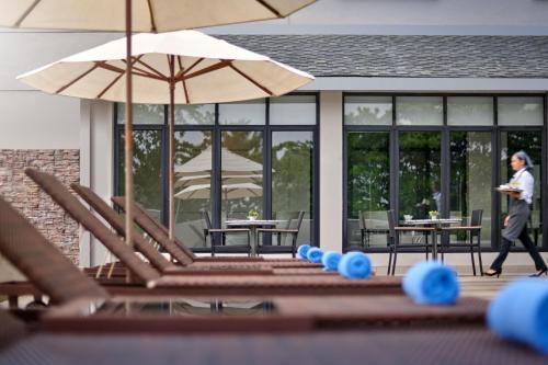 a woman walks past a patio with tables and an umbrella at AC Hotel by Marriott Kuantan in Kuantan