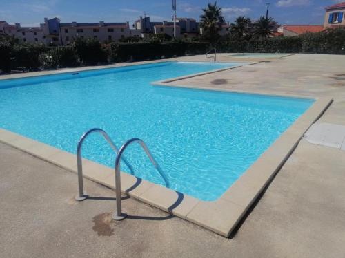 une grande piscine bleue avec une main courante en métal dans l'établissement Villa au Barcarès: Piscine, Parking, 2 Chambres, Terrasse Plein Sud, Proche Lac et Commodités - FR-1-782-22, au Barcarès