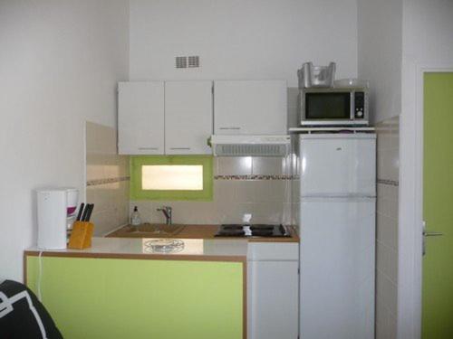 une cuisine avec des armoires blanches et un réfrigérateur blanc dans l'établissement Appartement T2 avec Terrasse, Parking, Proche Plage et Commerces - Le Barcarès - FR-1-782-40, au Barcarès