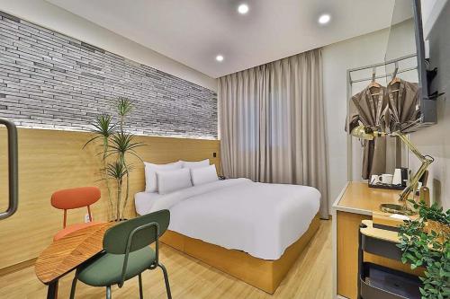 1 dormitorio con cama, escritorio y silla en Hotel Calmrest, en Geoje