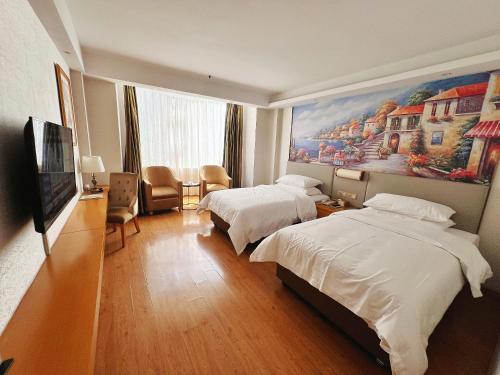 a hotel room with two beds and a painting on the wall at Foshan Shiwan Hotel in Foshan