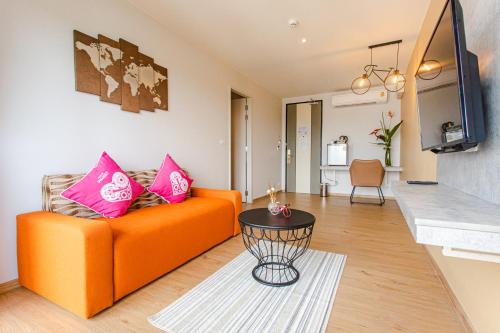 a living room with an orange couch and a table at Tour De Phuket Hotel - SHA Plus in Thalang