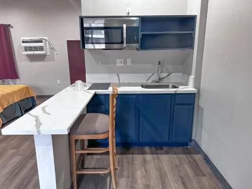 een kleine keuken met blauwe kasten en een wastafel bij El Cajon Inn & Suites in El Cajon