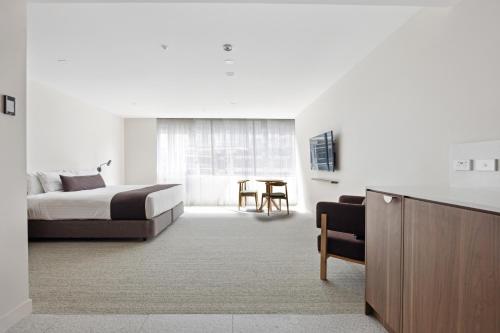 Habitación de hotel con cama y mesa en Abode Phillip, en Canberra