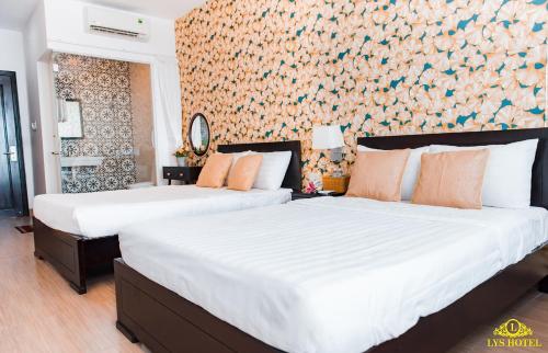 2 camas en un dormitorio con una pared con flores en Khách Sạn Nhơn Lý LYS HOTEL, en Quy Nhon