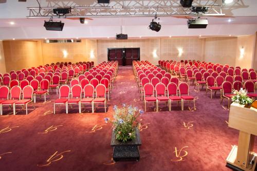 an empty hall with red chairs and a stage at Eden Andalou Aquapark & Spa in Marrakech