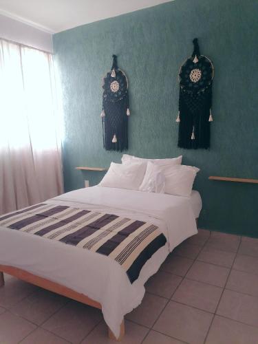 Un dormitorio con una cama grande y una pared verde en La casa gris, en Tulum