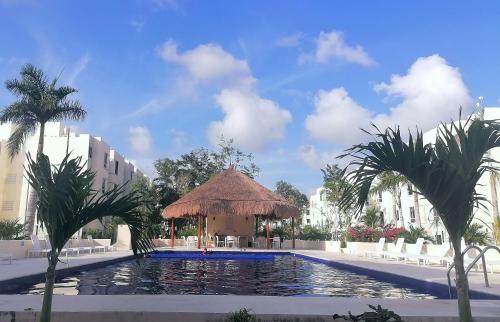a swimming pool with a gazebo and palm trees at La casa gris in Tulum