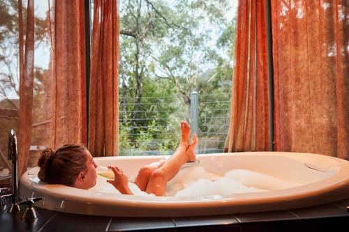 a woman laying in a bath tub in a window at Heavenly Retreat in Halls Gap