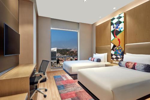 a hotel room with two beds and a desk and a window at Aloft Kathmandu Thamel in Kathmandu