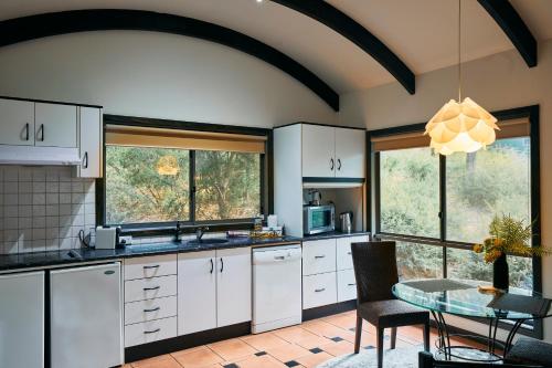 a kitchen with white cabinets and a table at Heavenly Retreat in Halls Gap