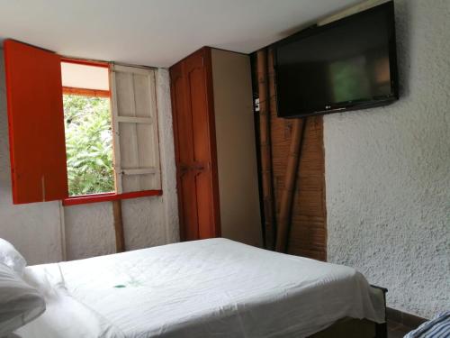 a bedroom with a bed and a flat screen tv at Cabaña rural con piscina in Manizales